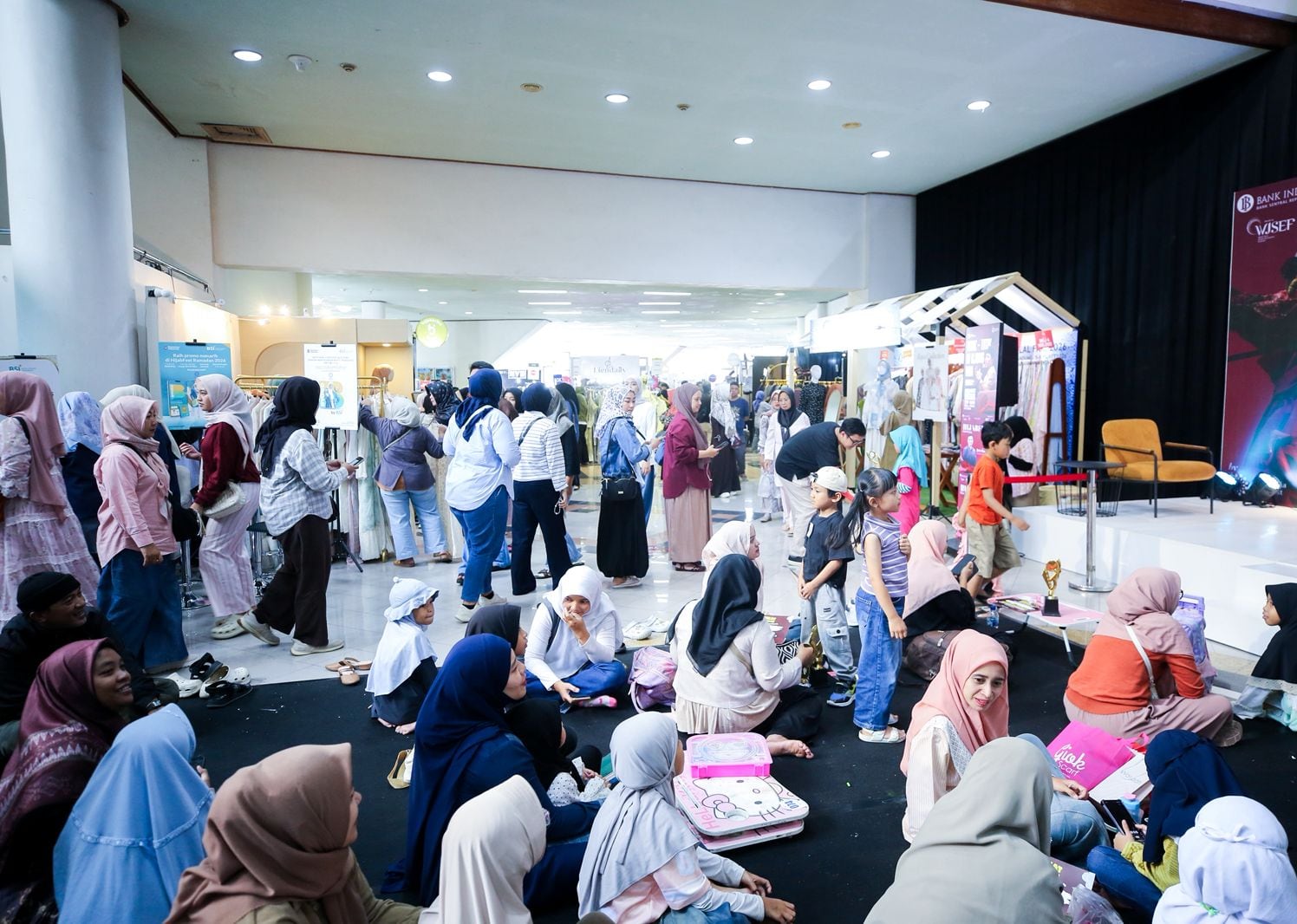 Visitors in modest fashion fill the main hall at Indonesia Hijabfest 2026 in Gedung Sabuga, Bandung, with brand booths along the aisle and the festival stage at right