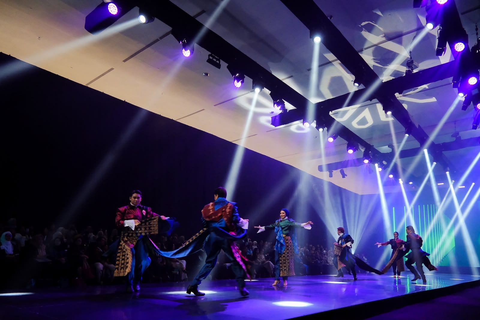 Dancers in richly patterned Indonesian wastra textiles perform under stage lights at the opening of IN2MOTIONFEST x JMFW 2026